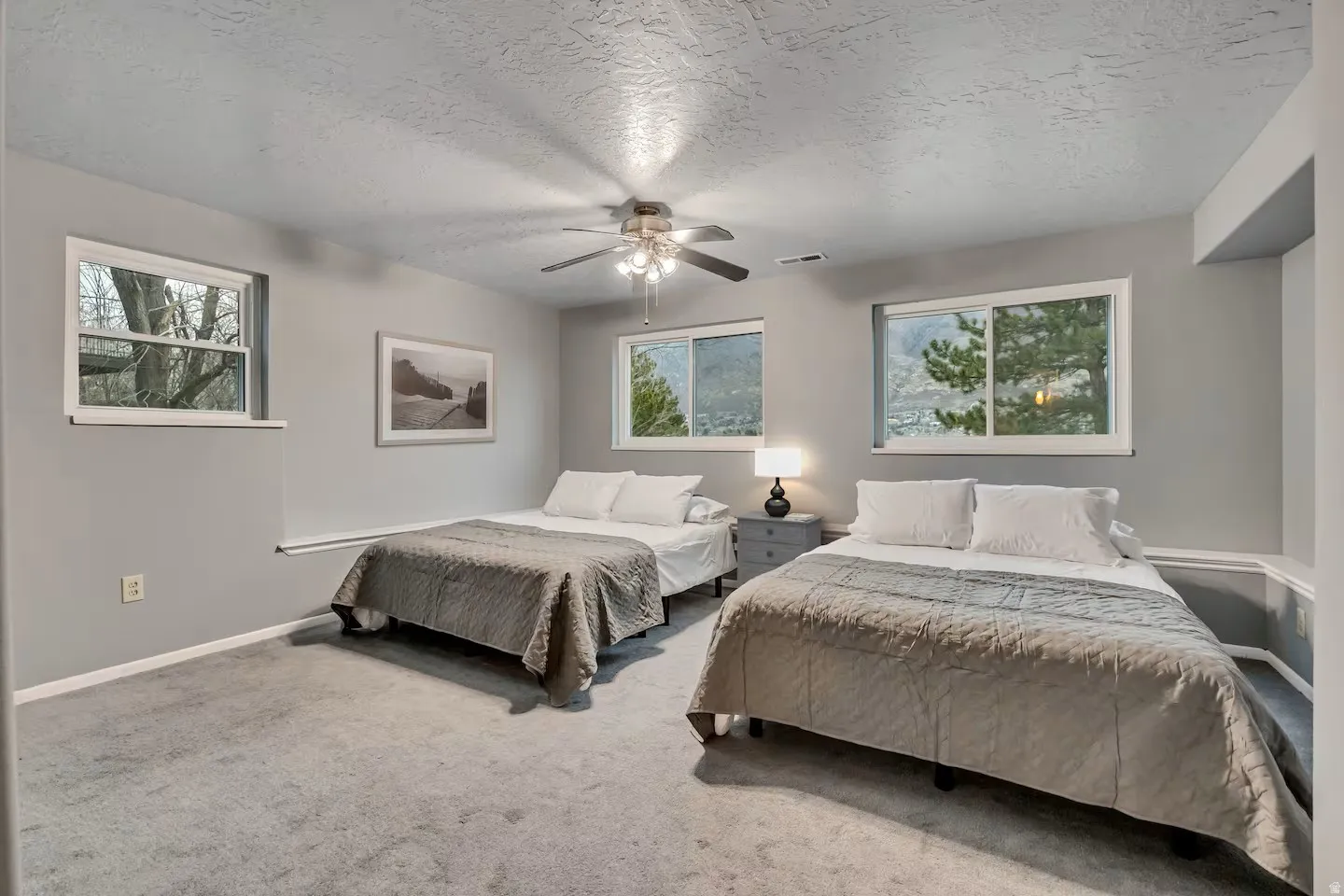 Bedroom with a textured ceiling, carpet flooring, and a ceiling fan