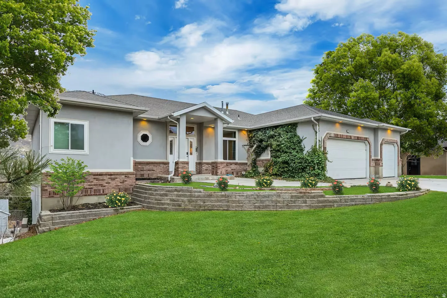 Ranch-style house featuring brick siding, an attached garage, a front yard, and stucco siding