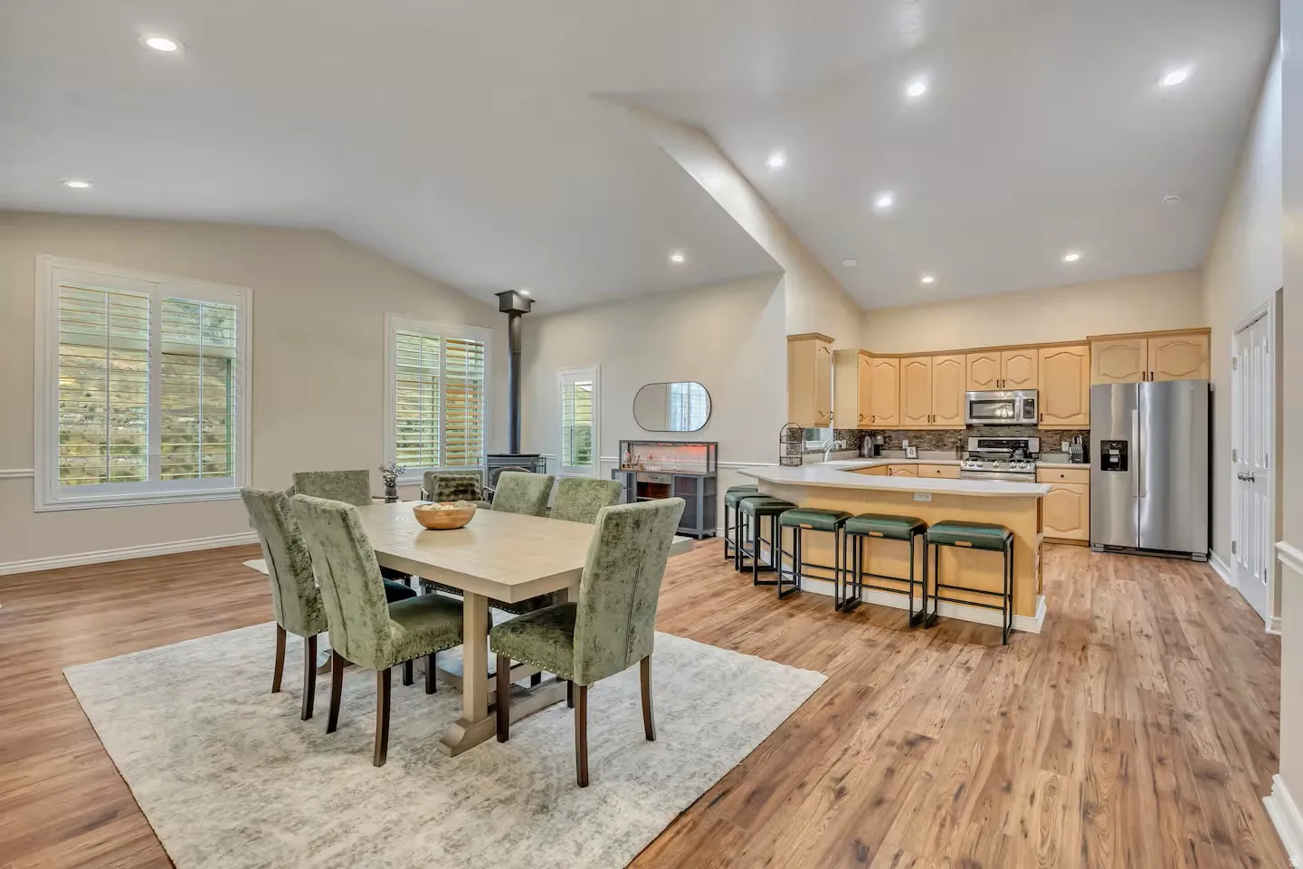 Dining area with recessed lighting, light wood-style flooring, vaulted ceiling, and a wood stove