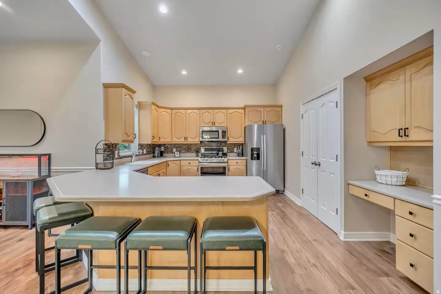 Kitchen with light wood finish cabinets, stainless steel appliances, light countertops, a breakfast bar area, and a peninsula