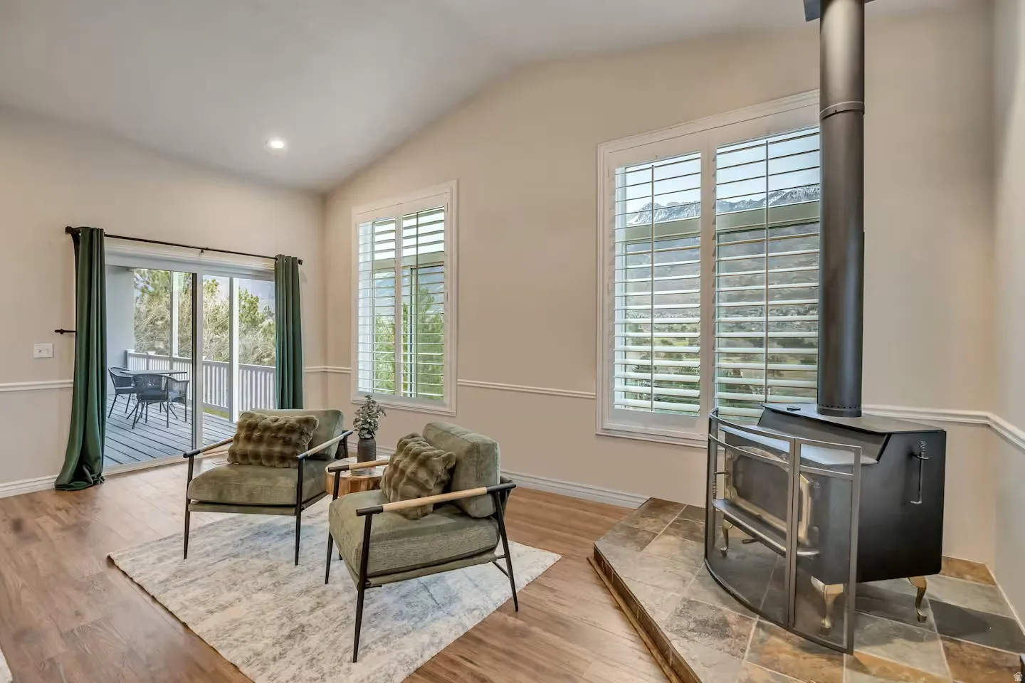 Sitting room featuring vaulted ceiling, a wood stove, wood finished floors, and recessed lighting