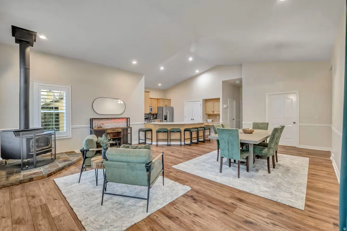 Dining room featuring a wood stove, light wood finished floors, vaulted ceiling, and recessed lighting