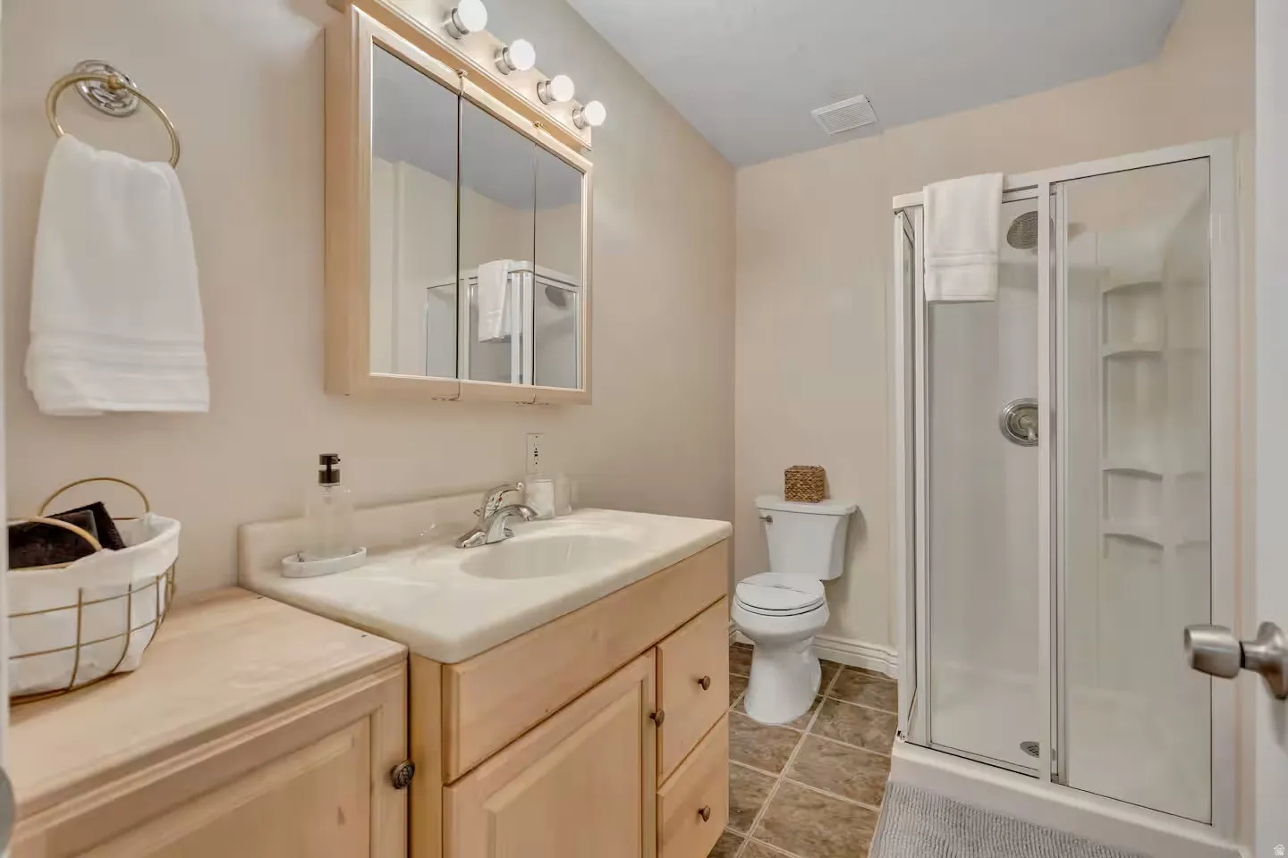 Full bathroom with a stall shower, vanity, and light tile patterned floors