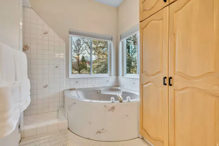 Full bathroom with a jetted tub and tile walls