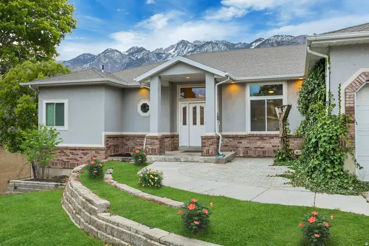 View of front of house featuring stucco siding, a front yard, a mountain view, and brick siding
