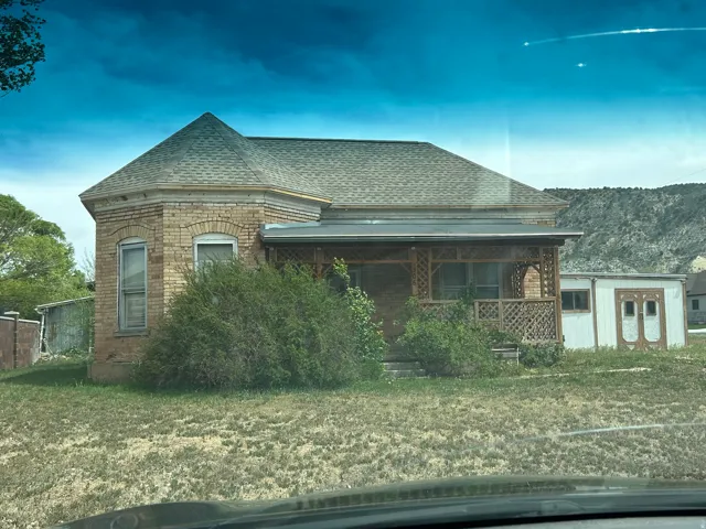 View of front of home with roof with shingles, brick siding, a porch, and a front yard