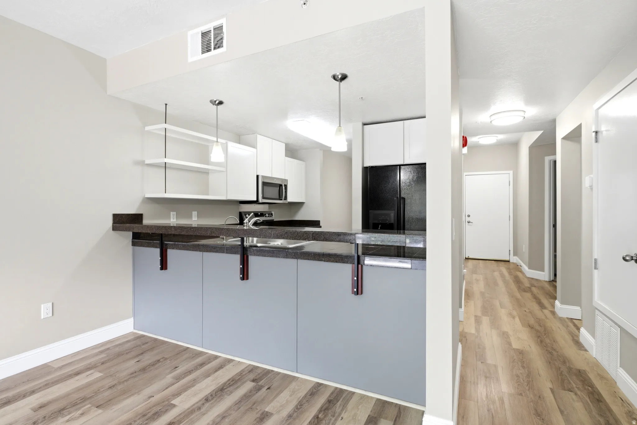 Kitchen featuring a dark stone-finish countertop, light gray base cabinetry, white upper cabinetry, and stainless steel appliances