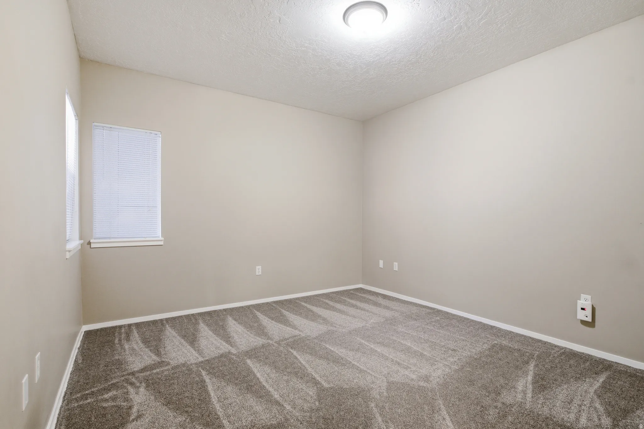 Unfurnished bedroom featuring closet, light colored carpet, and a textured ceiling