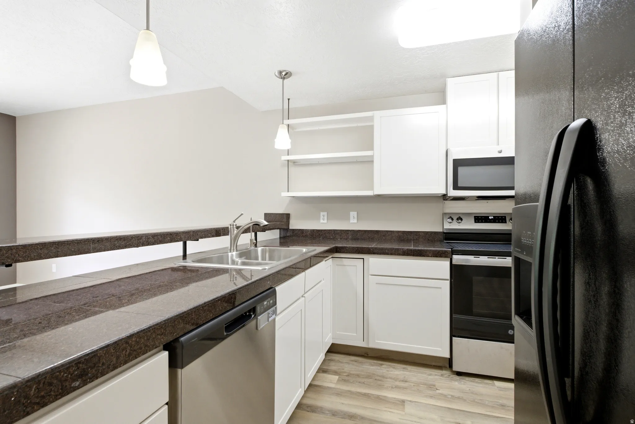 Kitchen featuring white cabinetry, dark stone-finish countertops, and wood-finish flooring