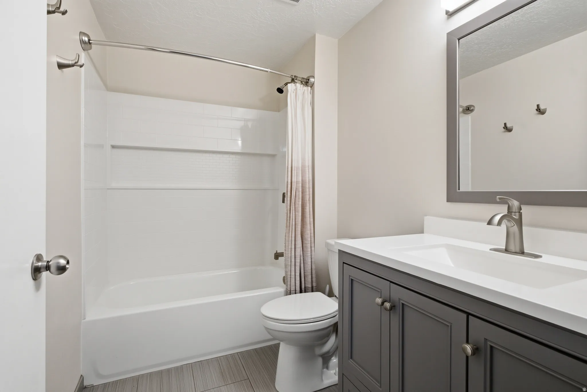 Full bath with vanity, a textured ceiling, and shower / bath combo with shower curtain