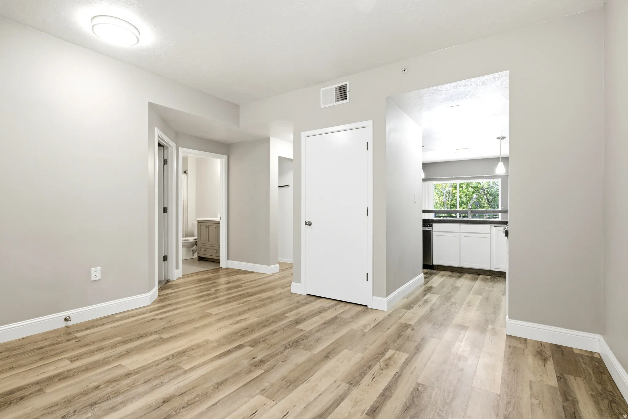 Spacious room featuring wood-finish flooring, light gray walls, and white baseboards