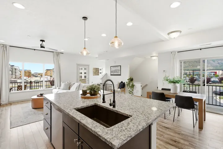 Kitchen featuring light wood-type flooring, an island with sink, open floor plan, and light stone counters