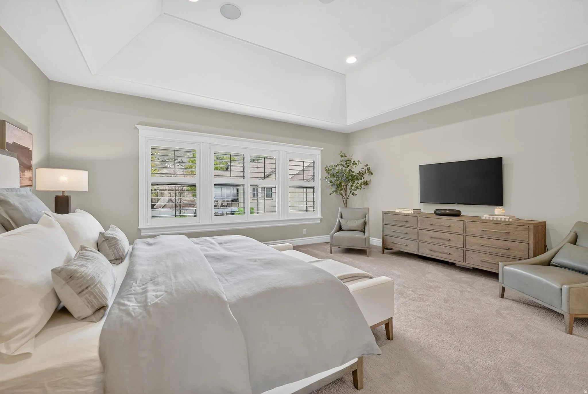 Bedroom featuring light carpet, a tray ceiling, and recessed lighting