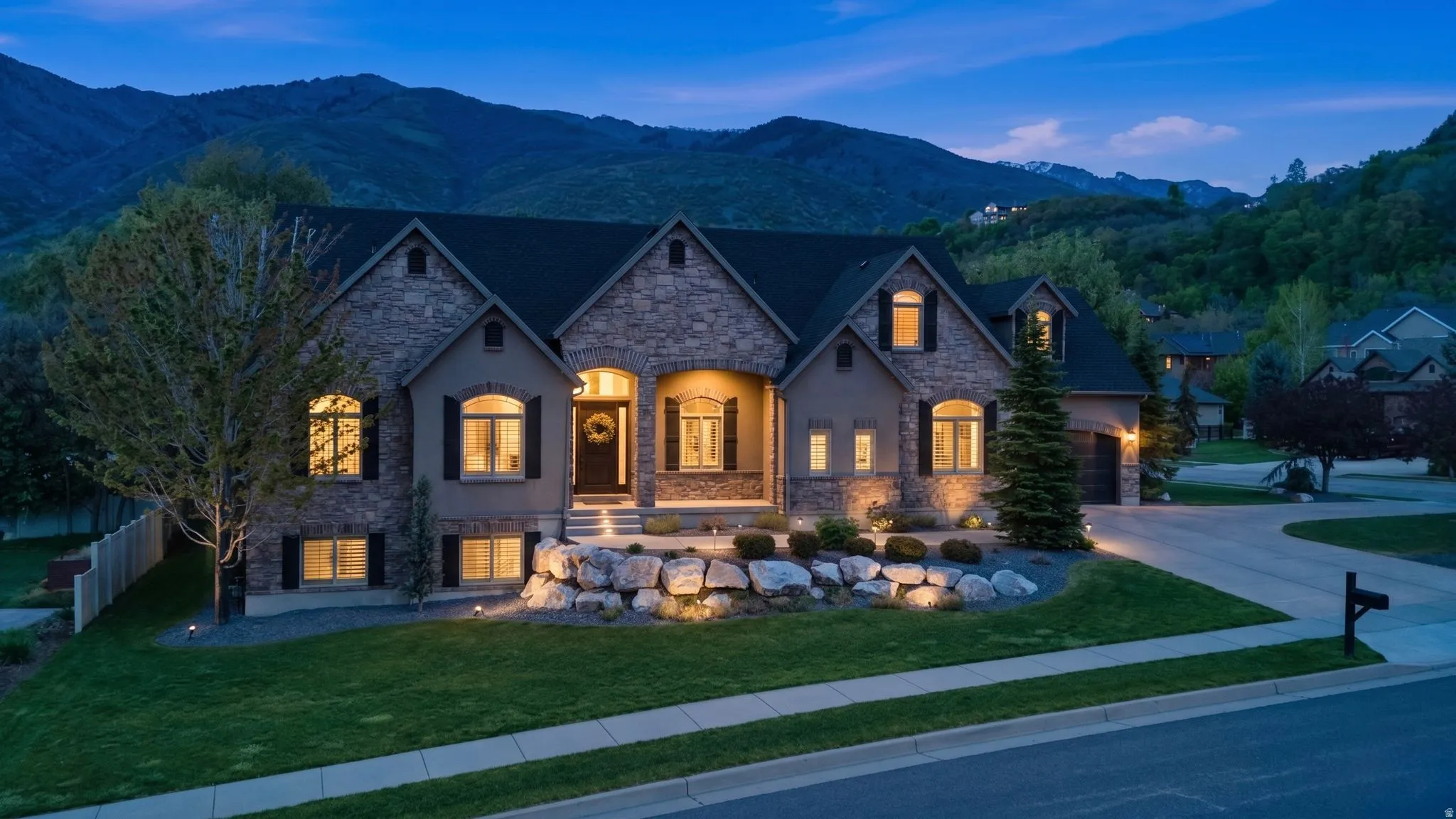 French country style house with stone siding, a yard, a mountain view, and concrete driveway