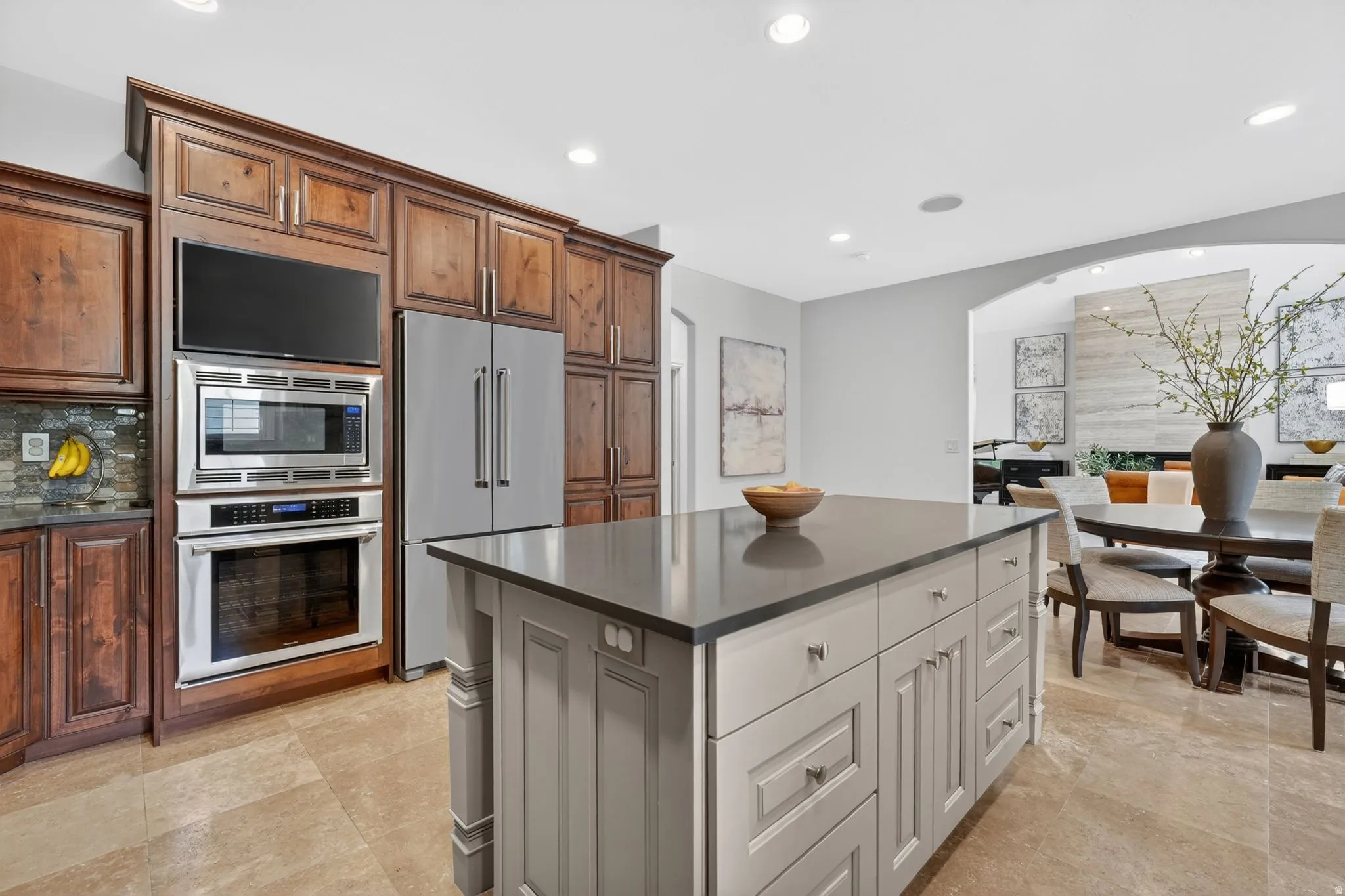 Kitchen featuring built in appliances, a kitchen island, arched walkways, recessed lighting, and tasteful backsplash