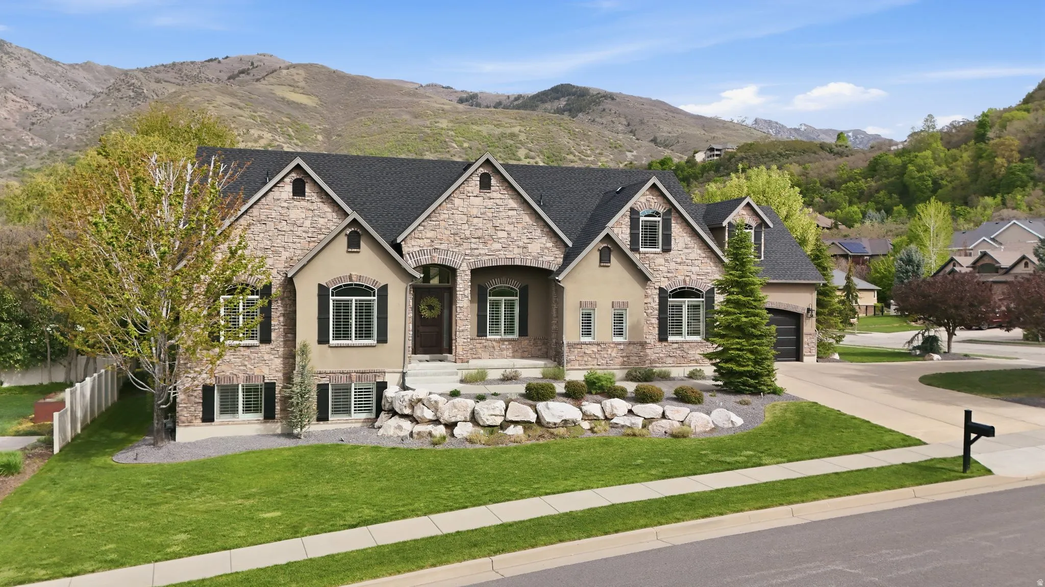 French country inspired facade with stone siding, a mountain view, stucco siding, and driveway