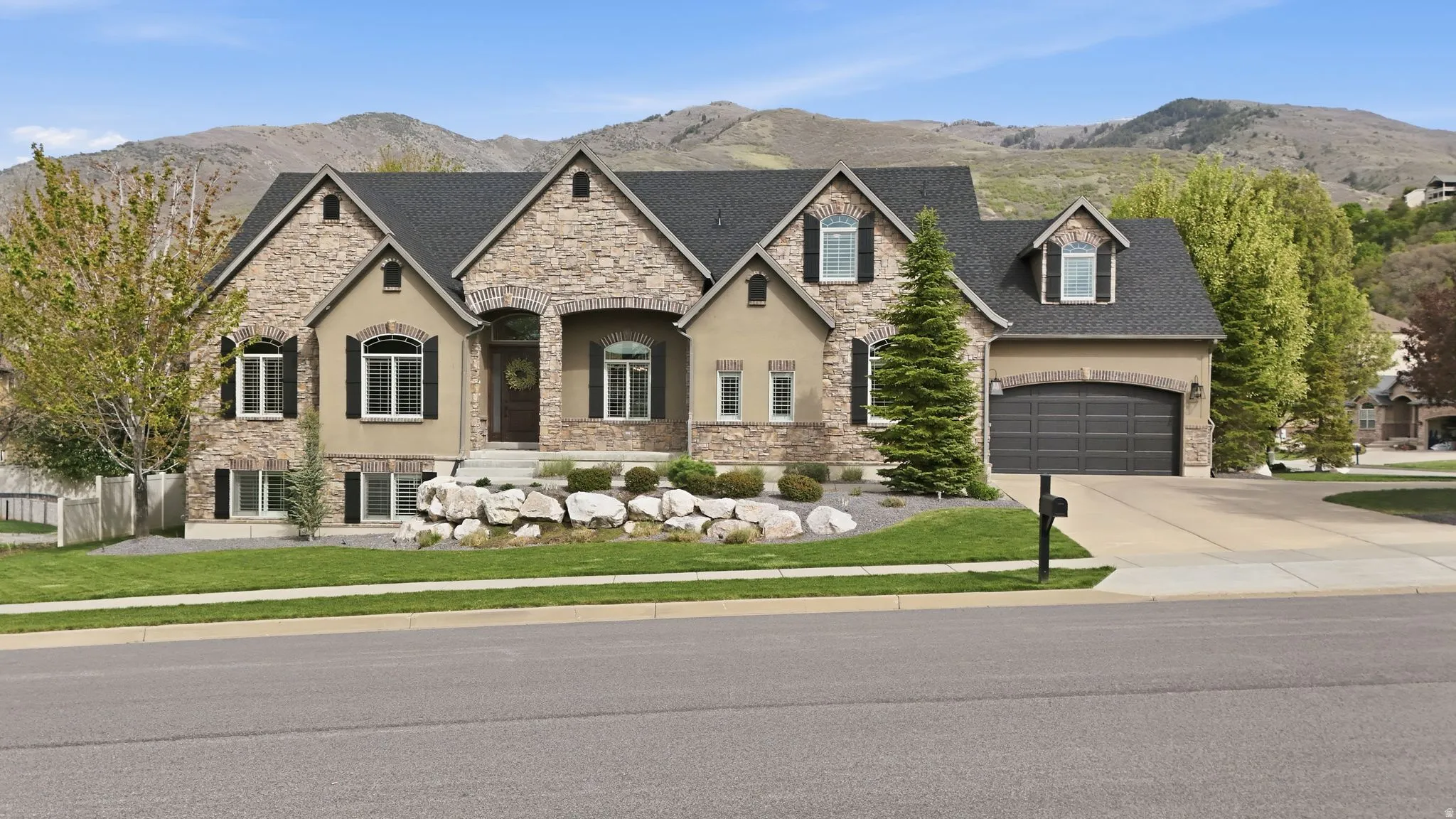 French country inspired facade featuring stone siding, stucco siding, and a mountain view