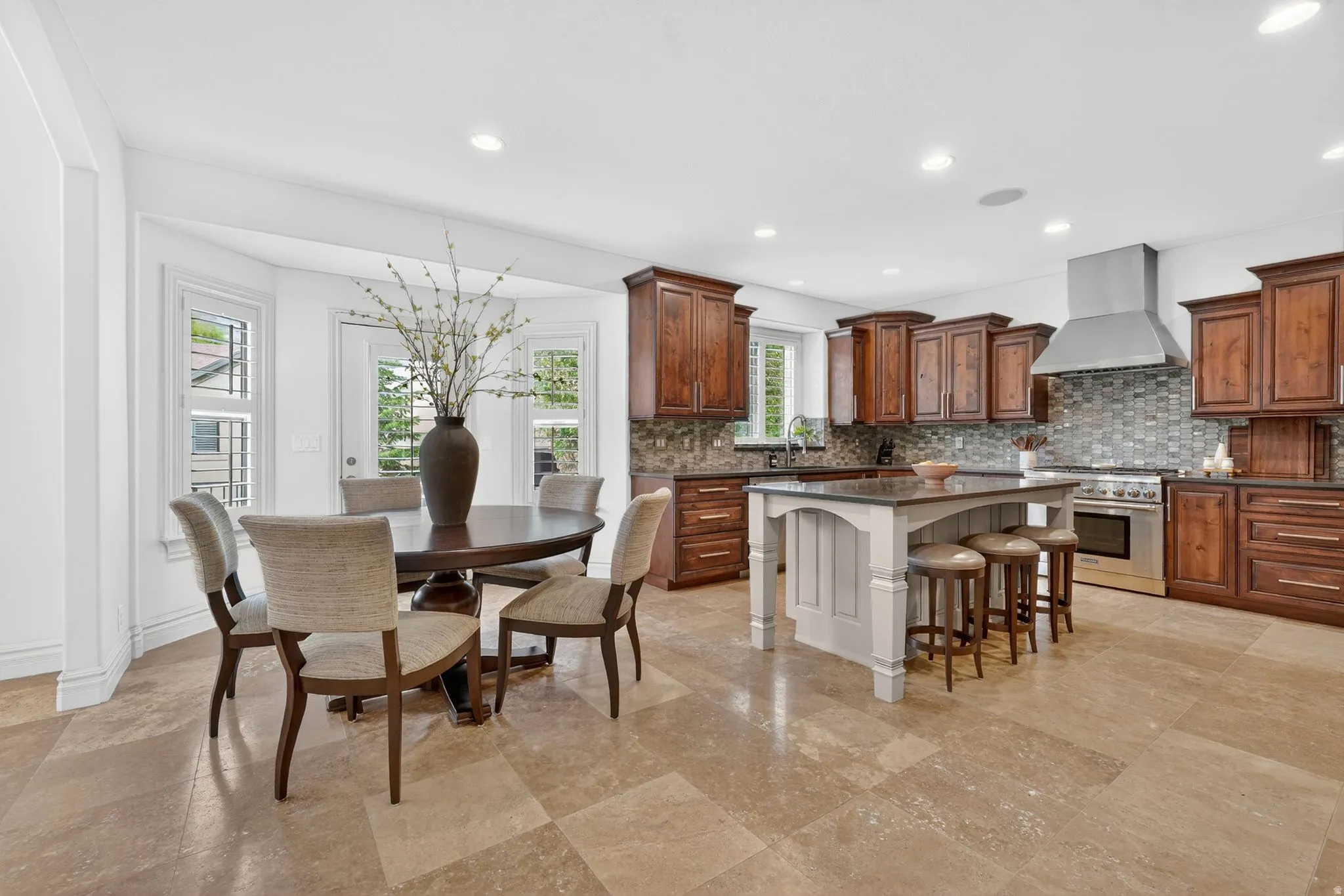 Kitchen featuring a kitchen breakfast bar, stainless steel stove, a kitchen island, dark stone counters, and recessed lighting
