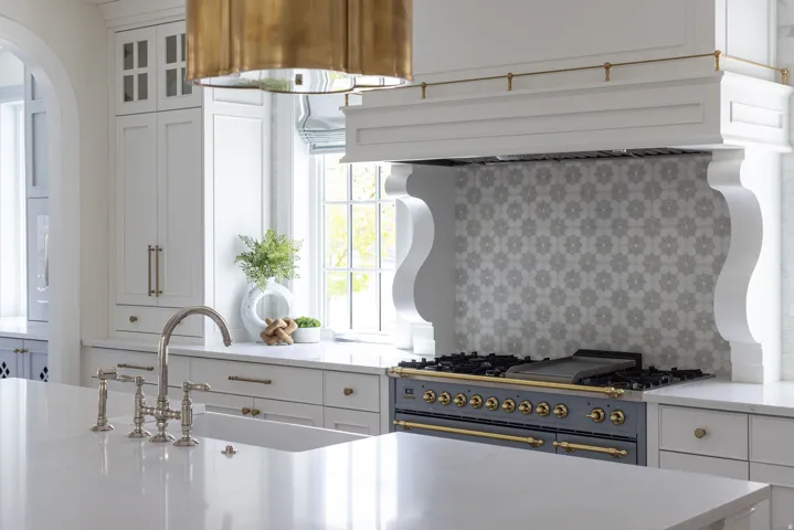 Kitchen featuring white cabinetry, light stone countertops, range with gas cooktop, glass fronted cabinets, and arched walkways