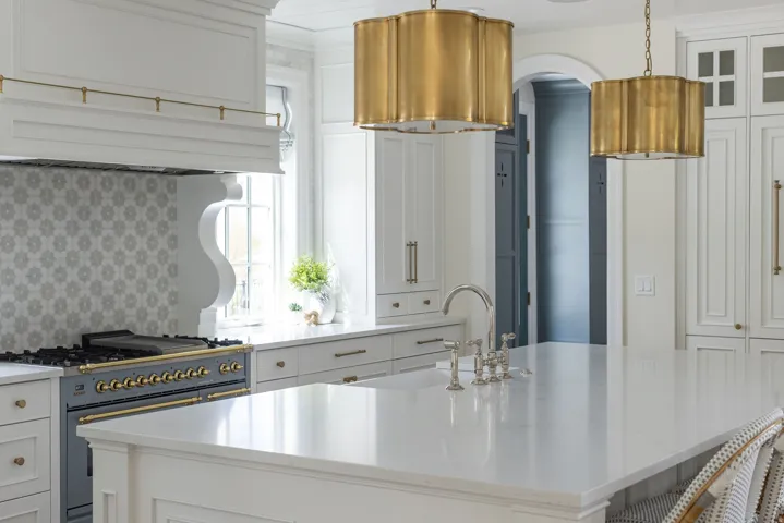 Kitchen with white cabinetry, gas range, light stone counters, and glass fronted cabinets