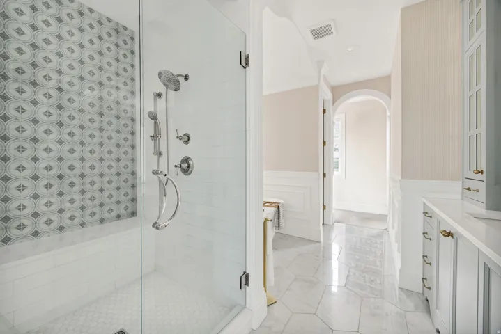 Full bath with a wainscoted wall, a shower stall, vanity, and a decorative wall