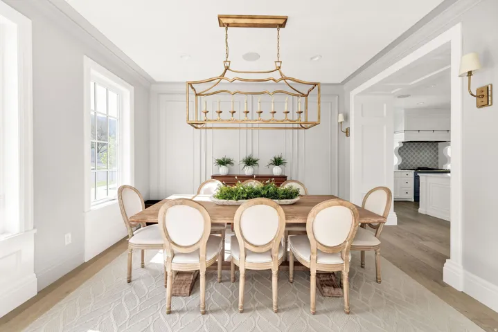 Dining area with light wood-type flooring, ornamental molding, and a decorative wall