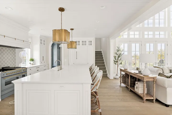 Kitchen with white cabinetry, double oven range, open floor plan, a center island with sink, and light wood finished floors