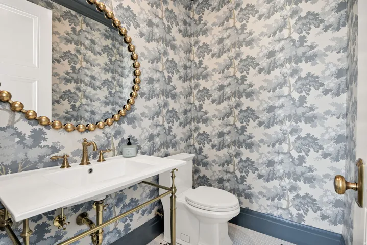 Half bathroom with a sink and wallpapered walls