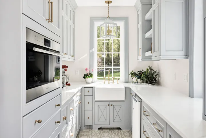 Kitchen featuring oven, gray cabinetry, light stone counters, pendant lighting, and glass insert cabinets