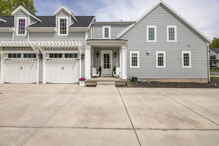 View of front of home with a porch, roof with shingles, and concrete driveway