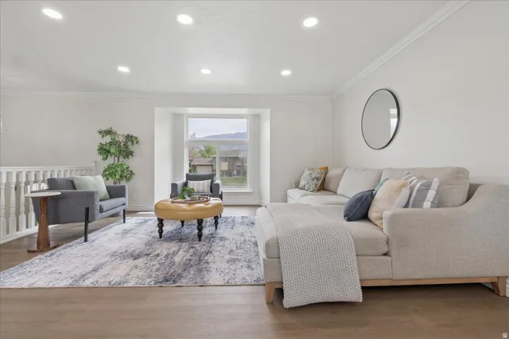 Living area with ornamental molding, wood finished floors, and recessed lighting