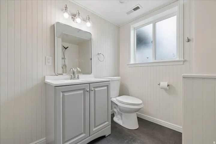 Full bathroom with vanity, crown molding, a shower, and wood walls