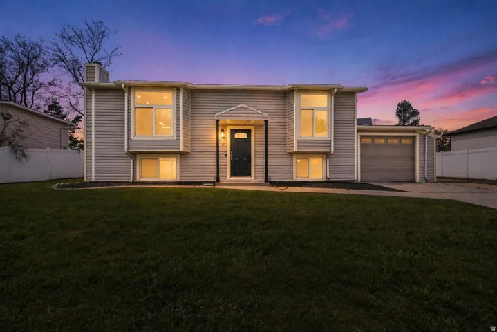 Split foyer home with a chimney, an attached garage, and concrete driveway