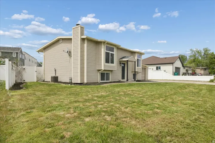 Back of house featuring a fenced backyard, a chimney, and a gate