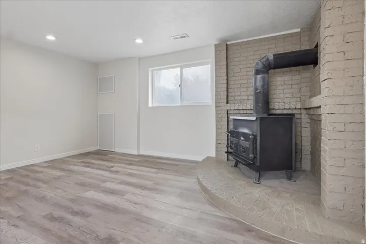 Unfurnished living room with a wood stove, light wood-style floors, and recessed lighting