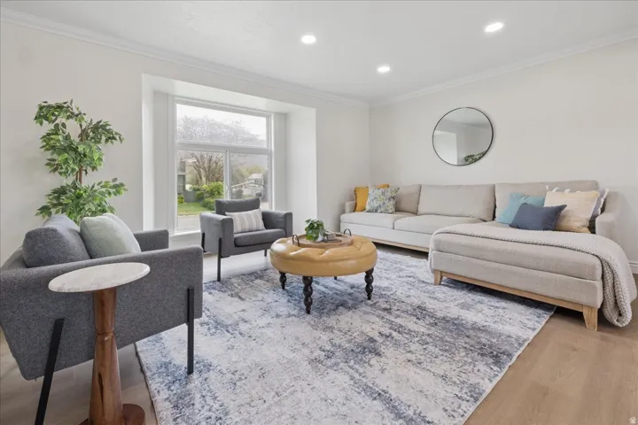Living room with crown molding, recessed lighting, and light wood-type flooring