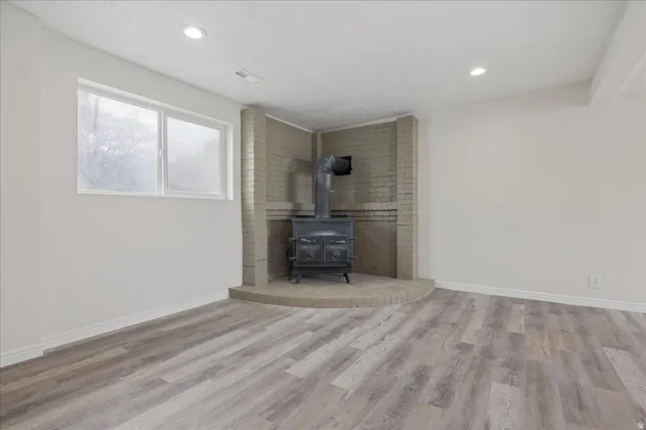 Unfurnished living room featuring light wood-style floors, a wood stove, and recessed lighting