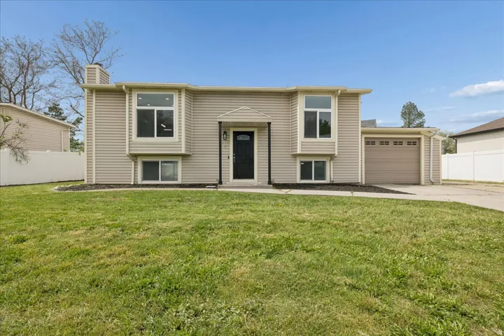 Split foyer home with a chimney, driveway, and an attached garage
