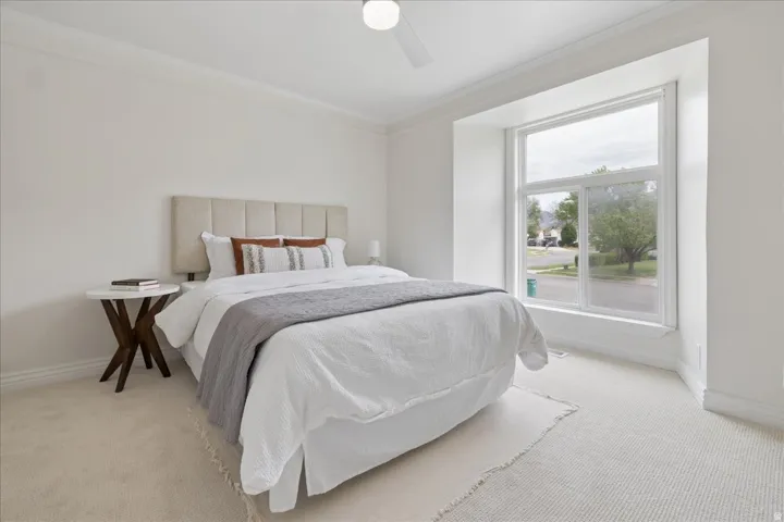 Bedroom featuring ornamental molding, light carpet, and a ceiling fan