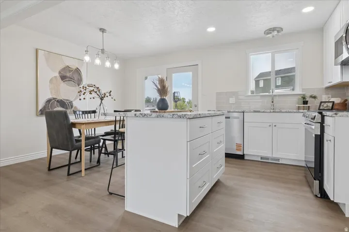 Kitchen featuring a kitchen island, white cabinets, backsplash, light stone countertops, and a textured ceiling
