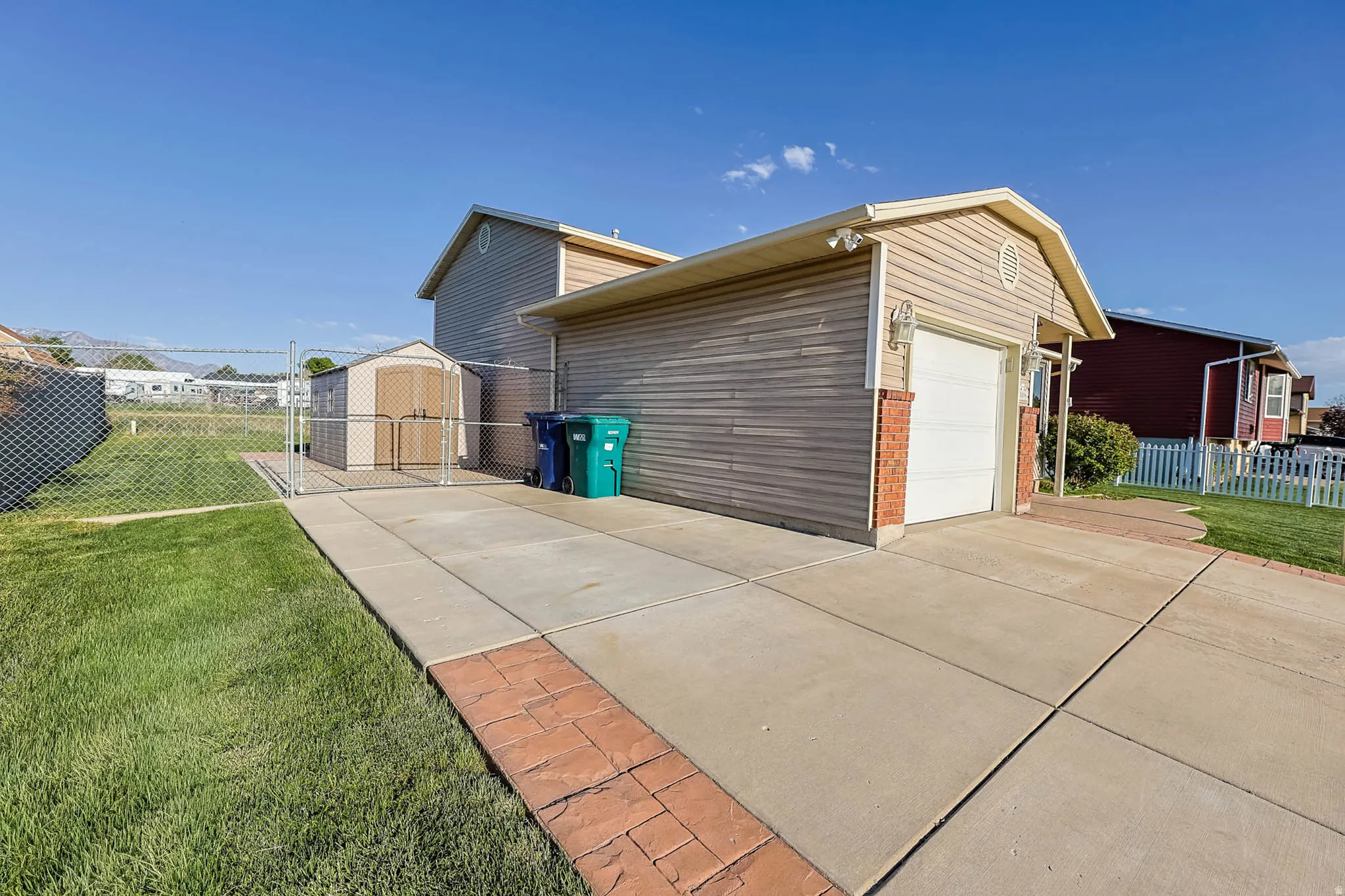 View of home's exterior featuring brick siding, driveway, an outbuilding, and an attached garage