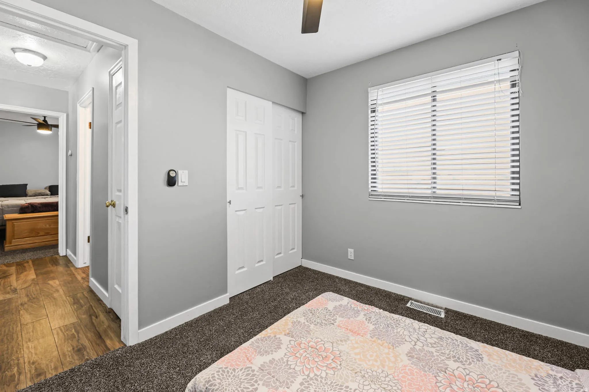 Bedroom featuring a closet, a textured ceiling, ceiling fan, and dark colored carpet