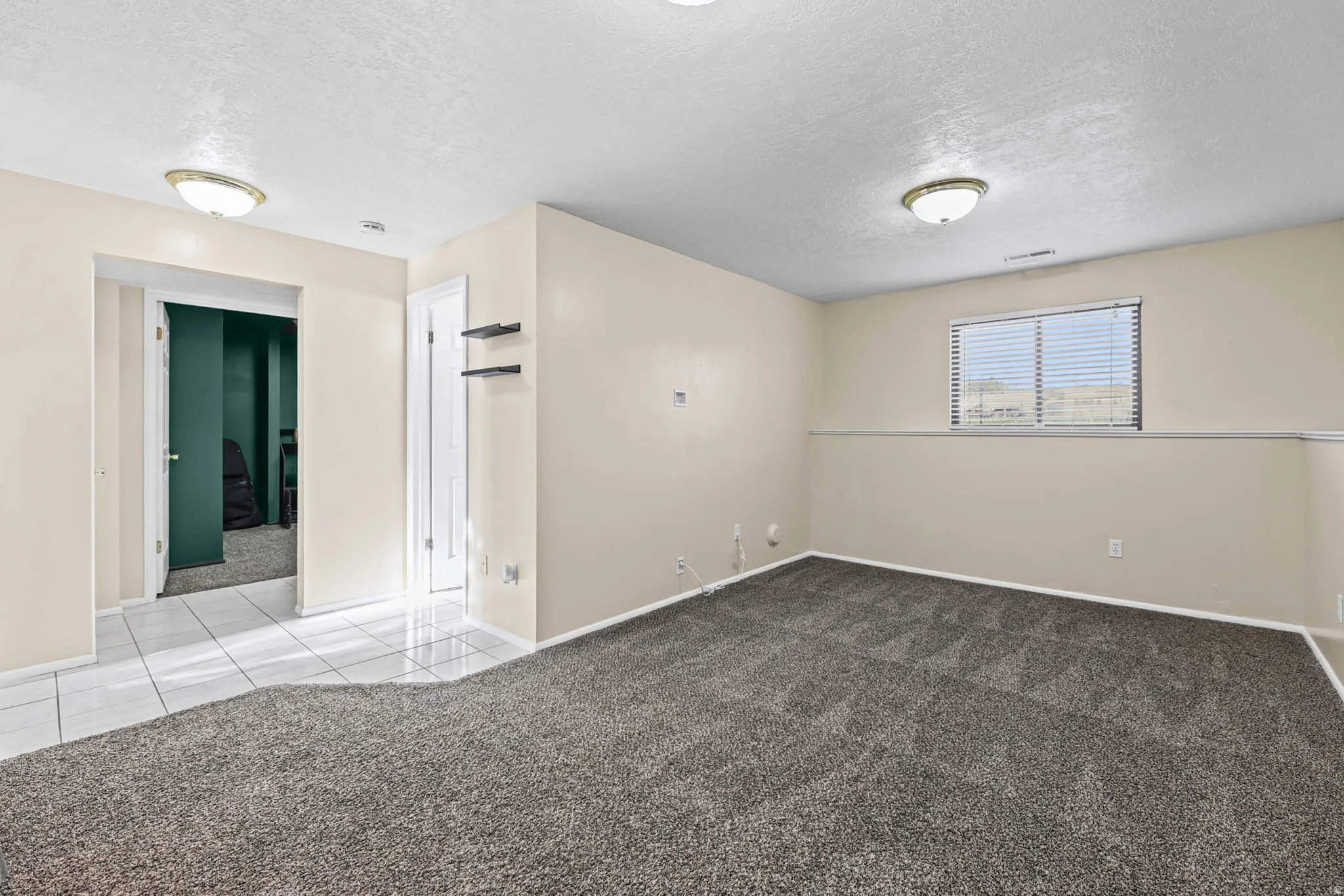 Tiled empty room featuring carpet flooring and a textured ceiling