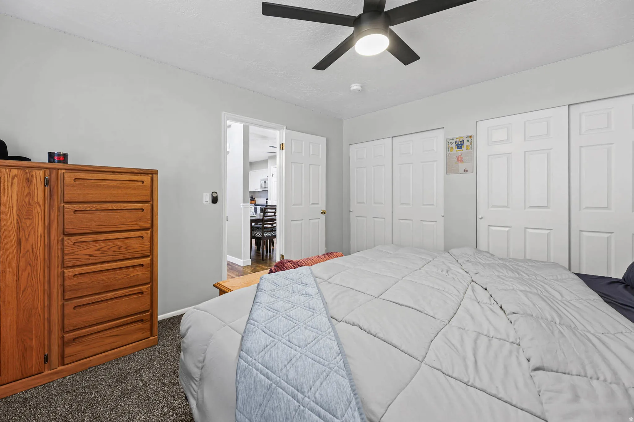 Bedroom with multiple closets, carpet floors, ceiling fan, and a textured ceiling