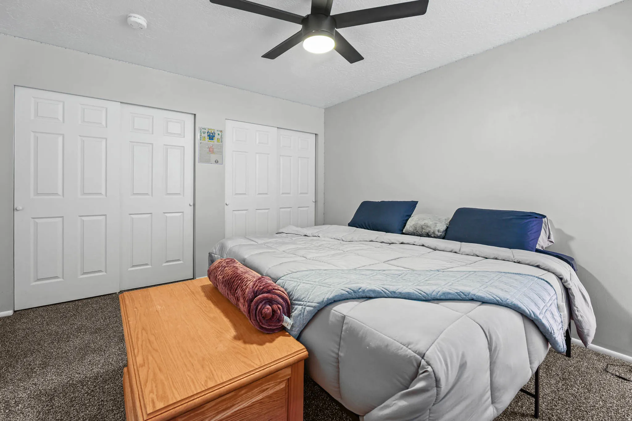 Carpeted bedroom with two closets, a textured ceiling, and a ceiling fan