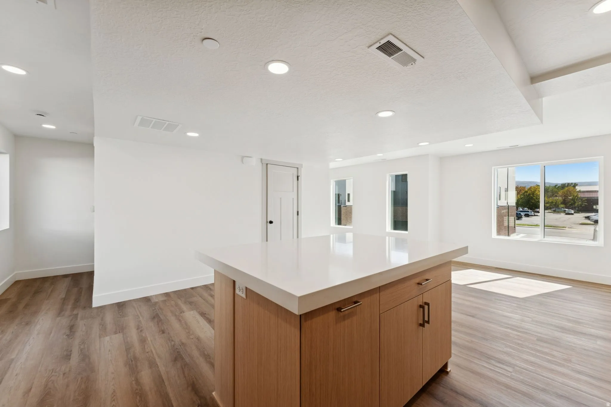 Kitchen with a center island, light wood-style flooring, recessed lighting, a textured ceiling, and wood finish cabinetry