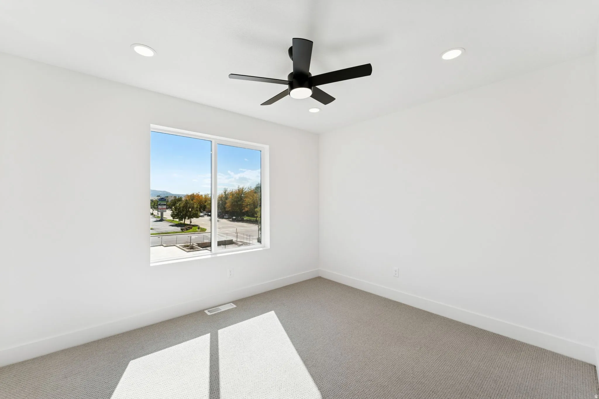 Spare room with carpet floors, a ceiling fan, and recessed lighting