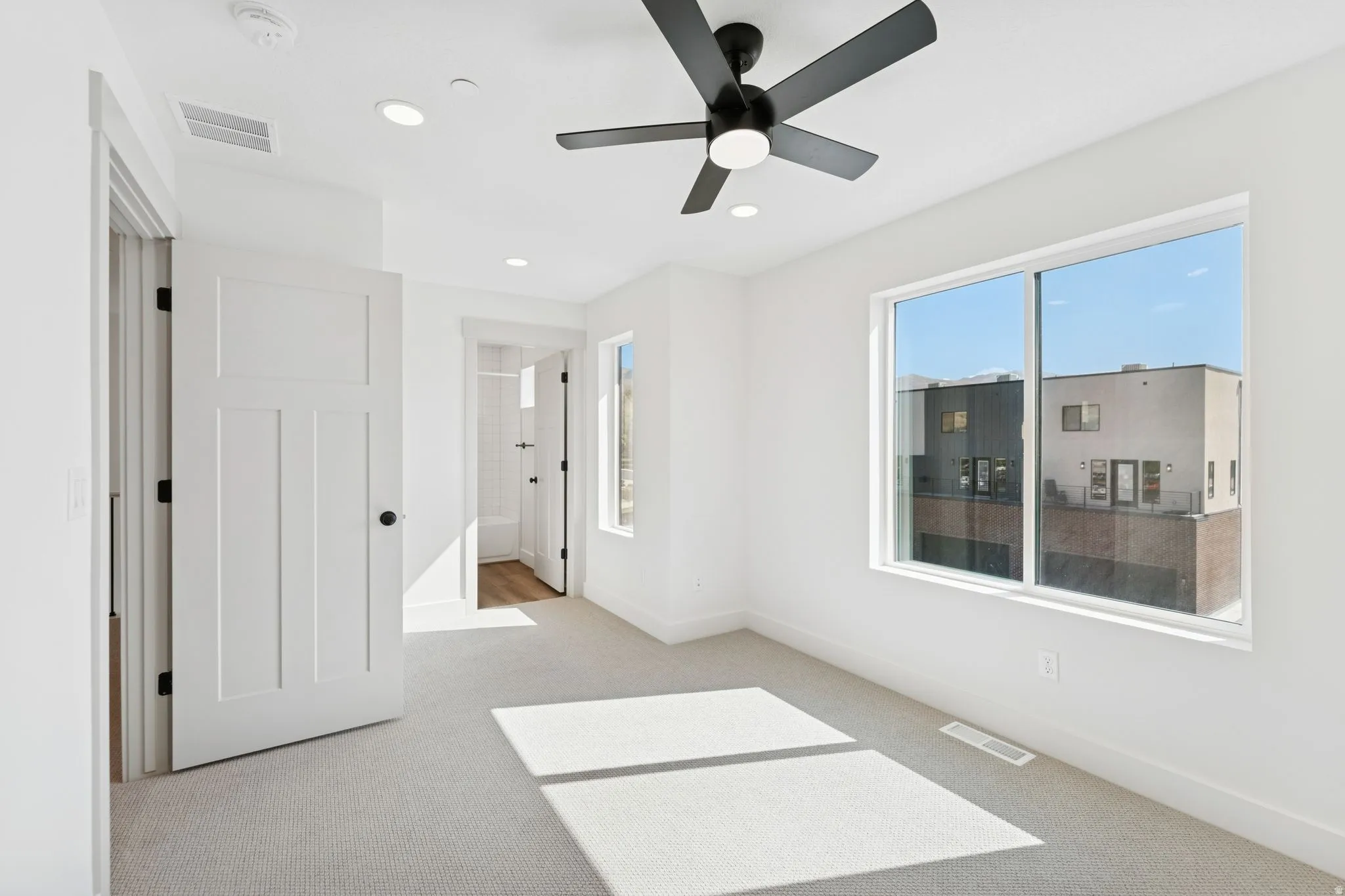 Unfurnished bedroom featuring light colored carpet, ensuite bath, a ceiling fan, and recessed lighting