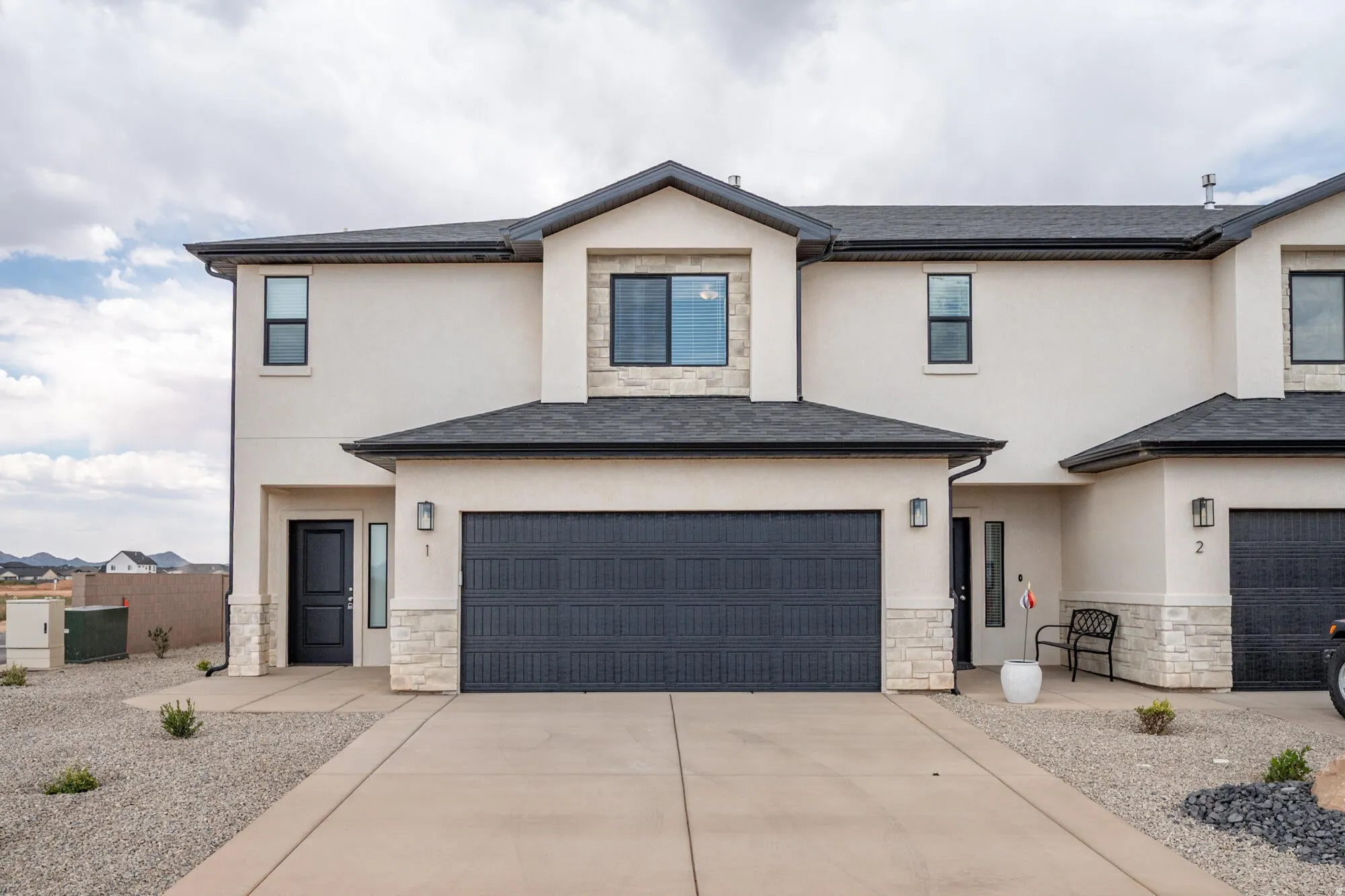 View of front of house with stone siding, stucco siding, concrete driveway, and a garage