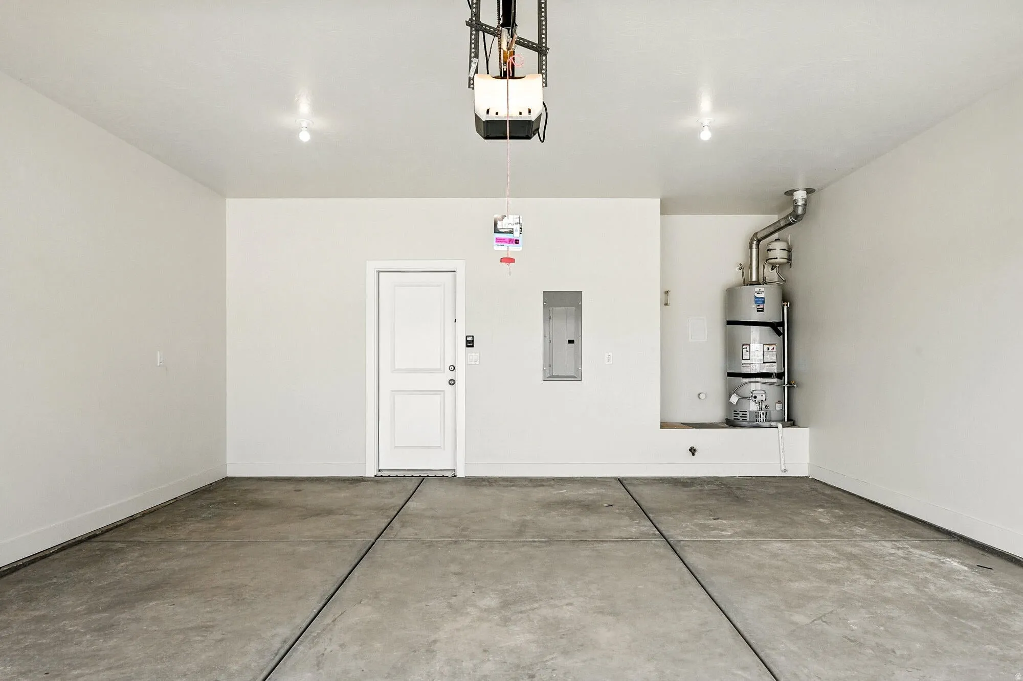 Garage featuring electric panel, secured water heater, and a garage door opener